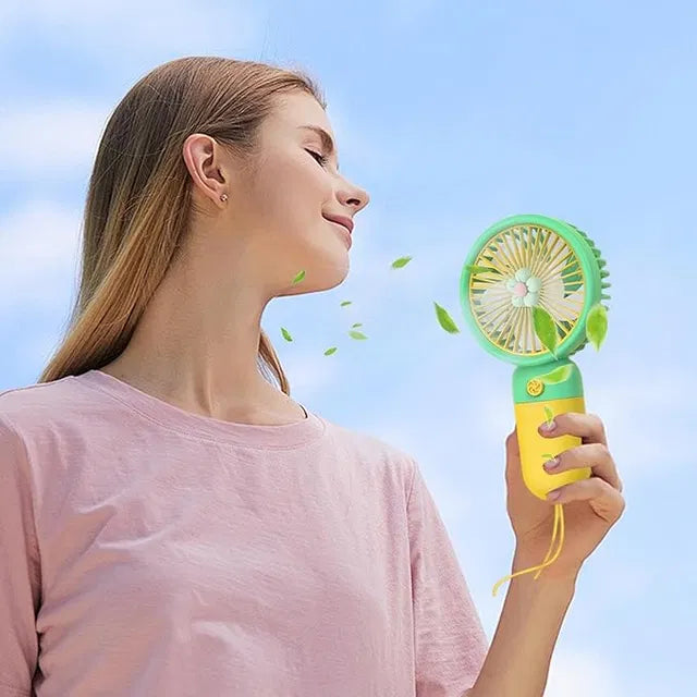 Woman holding a small green and yellow fan against a clear blue sky