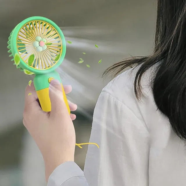 Person holding a green and yellow handheld fan with a blurred background